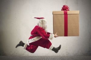 Santa carrying huge parcel wrapped with bow